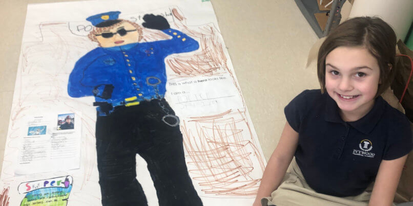 Ivywood student sitting next to her life size drawing of a police officer
