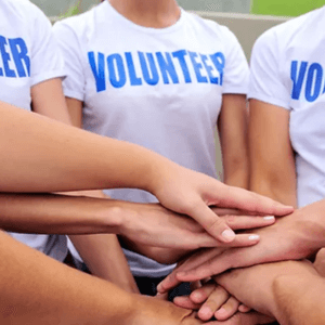 people with their hands together wearing volunteer shirts